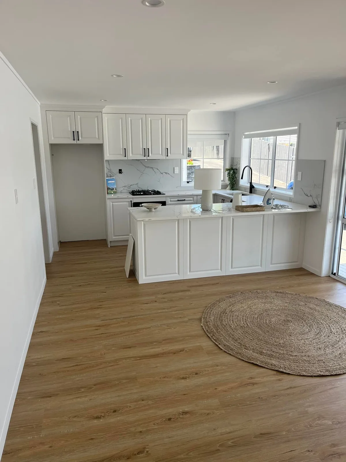 Completed white kitchen renovation with a stone waterfall island in Auckland